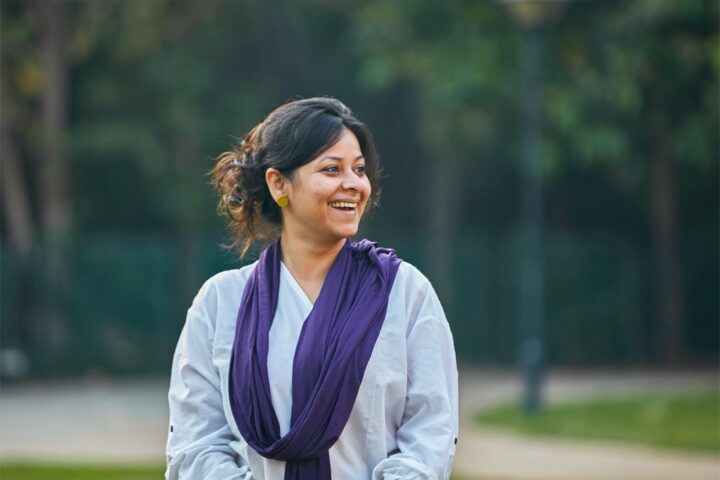 A facilitator outdoors in a white kurta and purple scarf