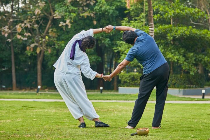 Two participants on the lawn, holding hands in a paired stretch