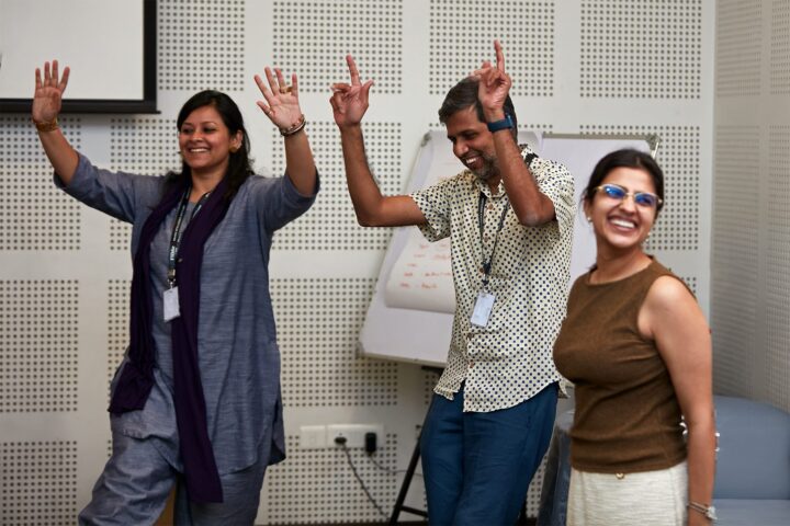 A facilitator leading a movement exercise, participants following with arms raised