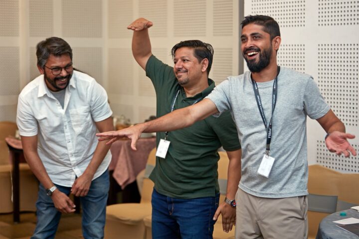 Three participants indoors, arms outstretched in a group exercise