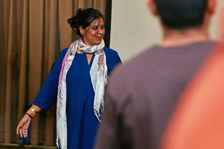 A facilitator indoors in a blue kurta and scarf