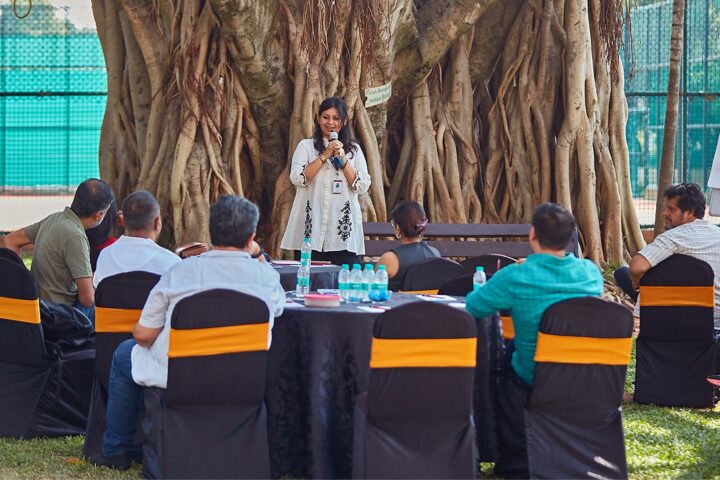 A session under the banyan tree, participants seated in a semicircle