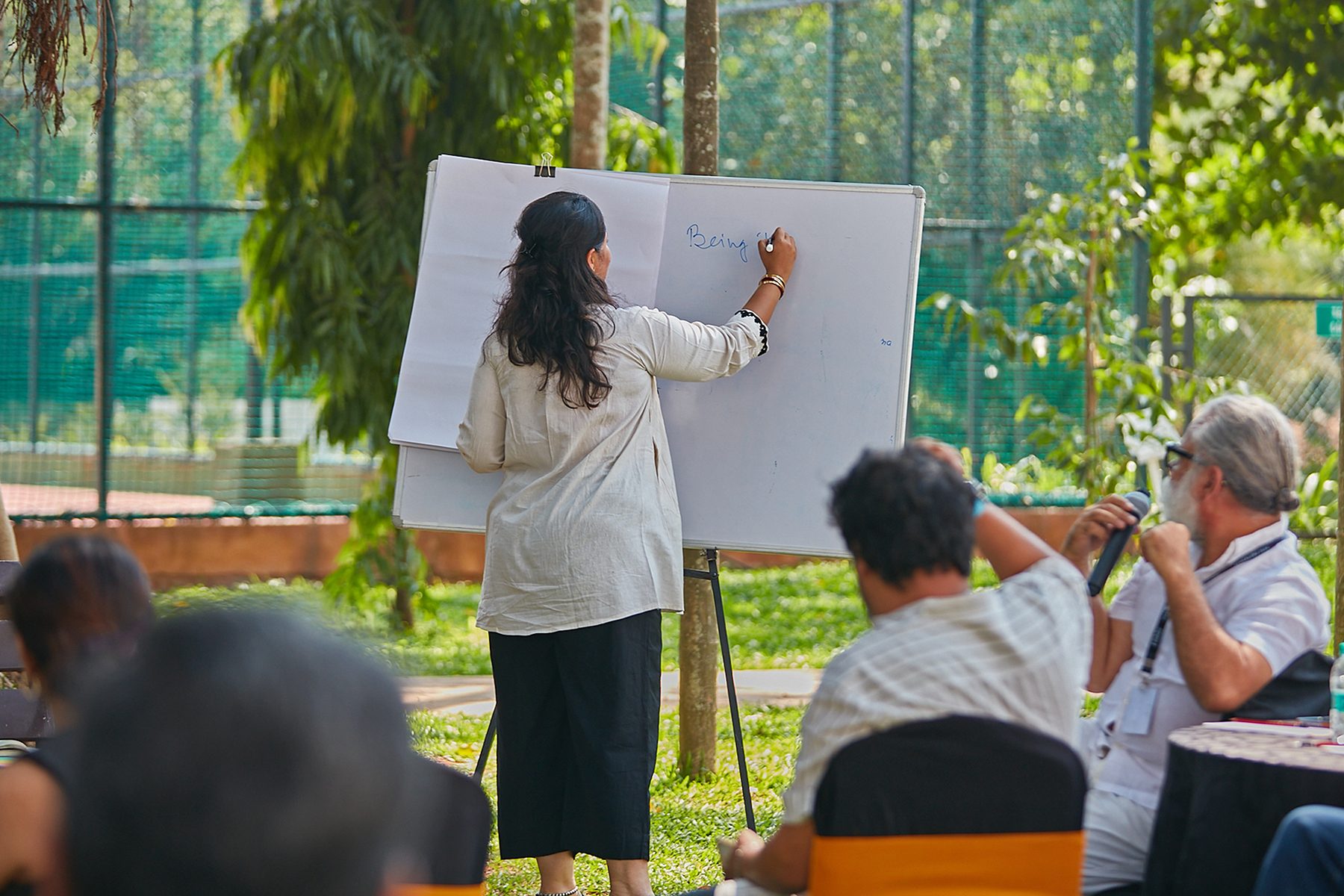 A participant indoors, smiling, as another person reaches towards her during a group exercise.