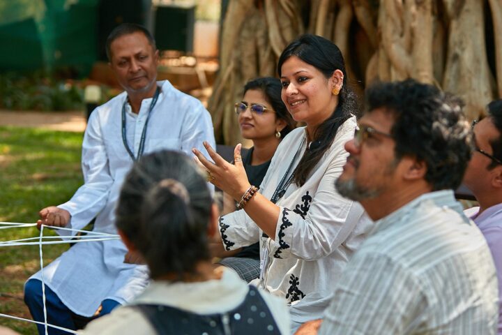 Participants seated outdoors holding a web of string between them