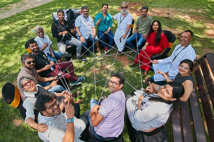 Overhead group photograph, participants holding a web of string and looking up