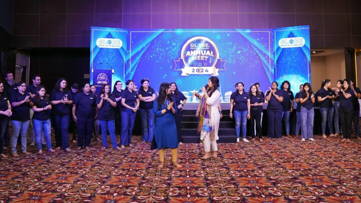 A wide view of the stage, a facilitator addressing a line of participants