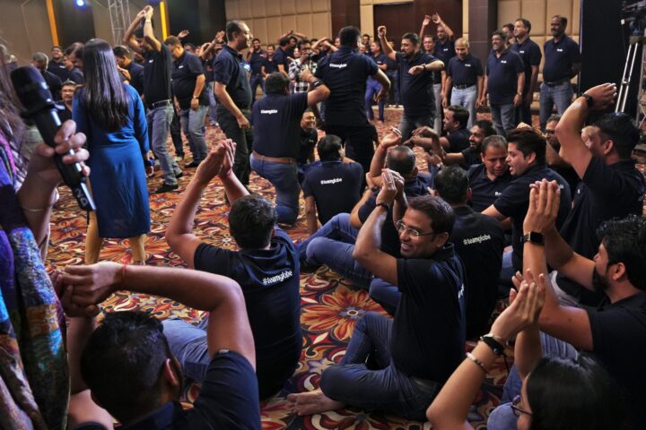 Participants with arms raised in the crowd, one holding a microphone aloft