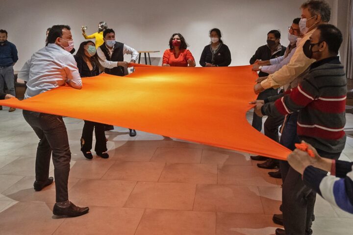 Participants around a large orange cloth held stretched between them