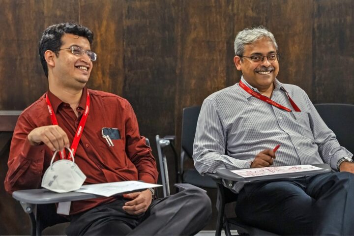 Two participants seated side by side, holding the drawings they have made