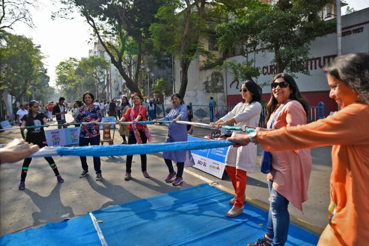 A long blue cloth stretched down the middle of the closed road, held by women on both sides