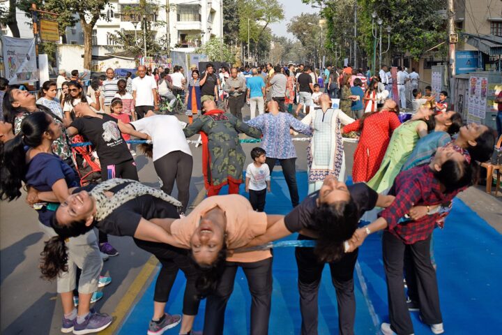 A wide view of the crowded street, several participants leaning back into a supported arch