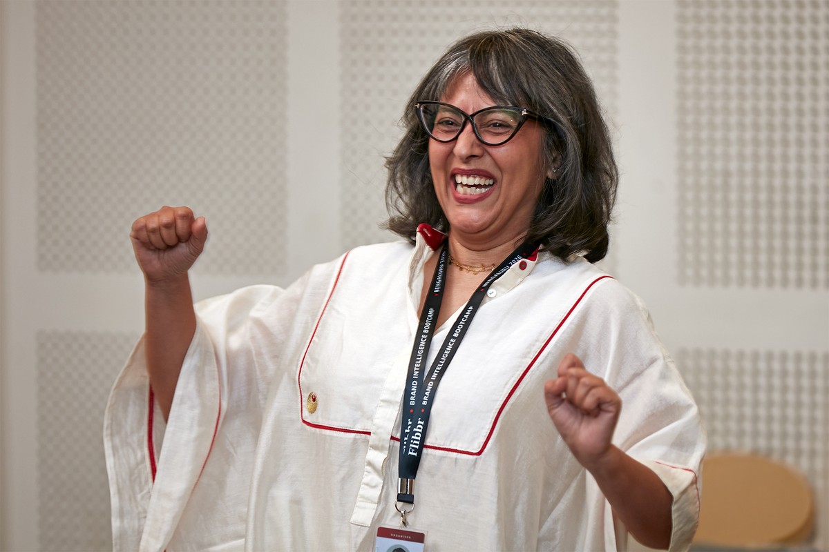 A workshop participant laughing with both fists raised during an indoor group session.