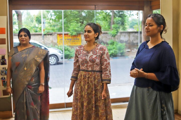 Three participants standing still with their eyes closed, daylight behind them through a glass door