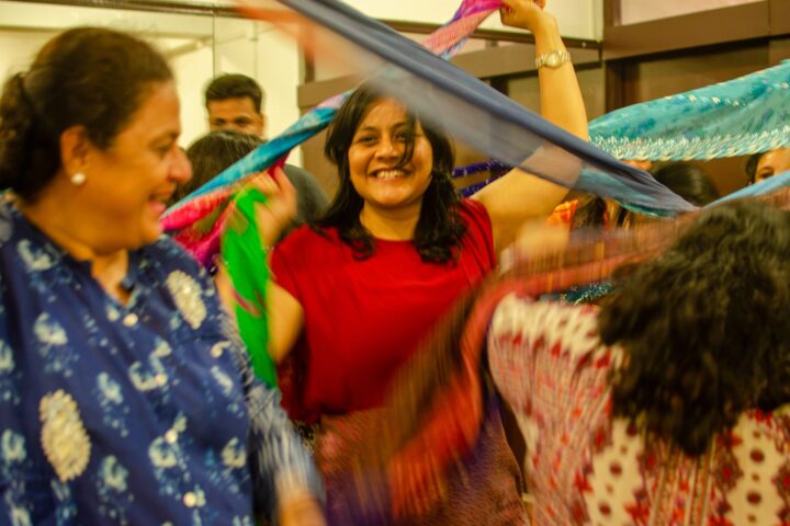 Two participants laughing with their arms raised as a strip of cloth passes overhead