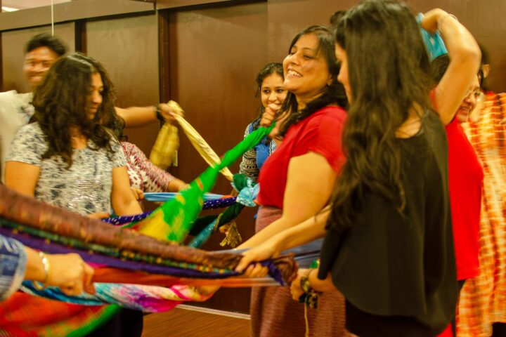 A circle of participants holding a long braided length of cloth between them