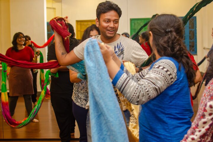 Two participants working a length of pale blue cloth between them
